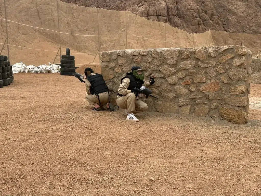 Paintball players taking cover behind a stone wall during match in Sharm El Sheikh