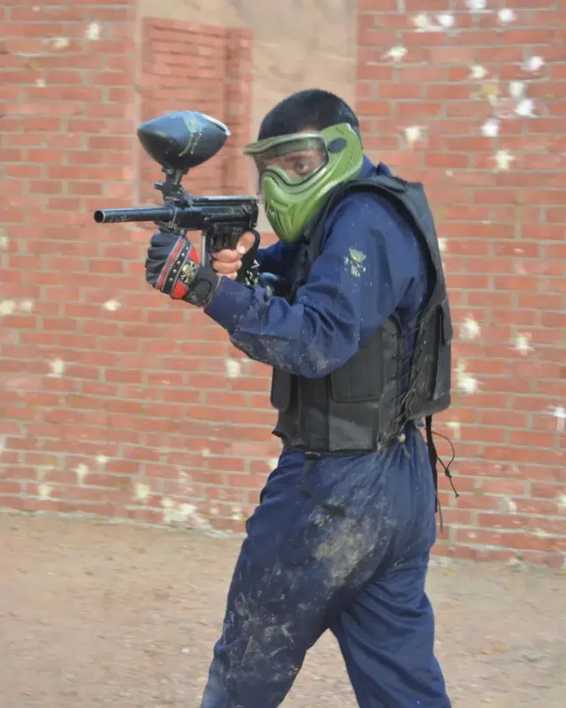 Paintball player in protective mask shooting during game in Sharm El Sheikh desert arena