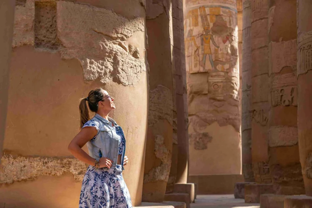 Tourist posing in front of ancient Egyptian stone columns at Luxor temple